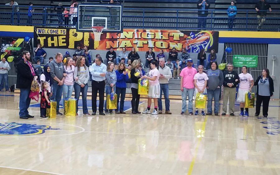 The seniors of the varsity girls basketball team standing with their parents. From left to right (students): Ceudah Hajashafira, Shelby Henschen, Jessica Vandiver, Lanie Allen, Kendaya Mapes, and Abbie Peterson