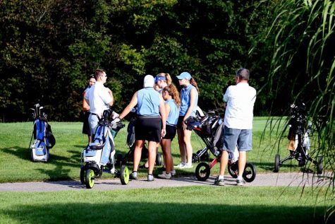 The Girls Golf team huddles around coach Mr. Ryan Eakins for a team meeting. 